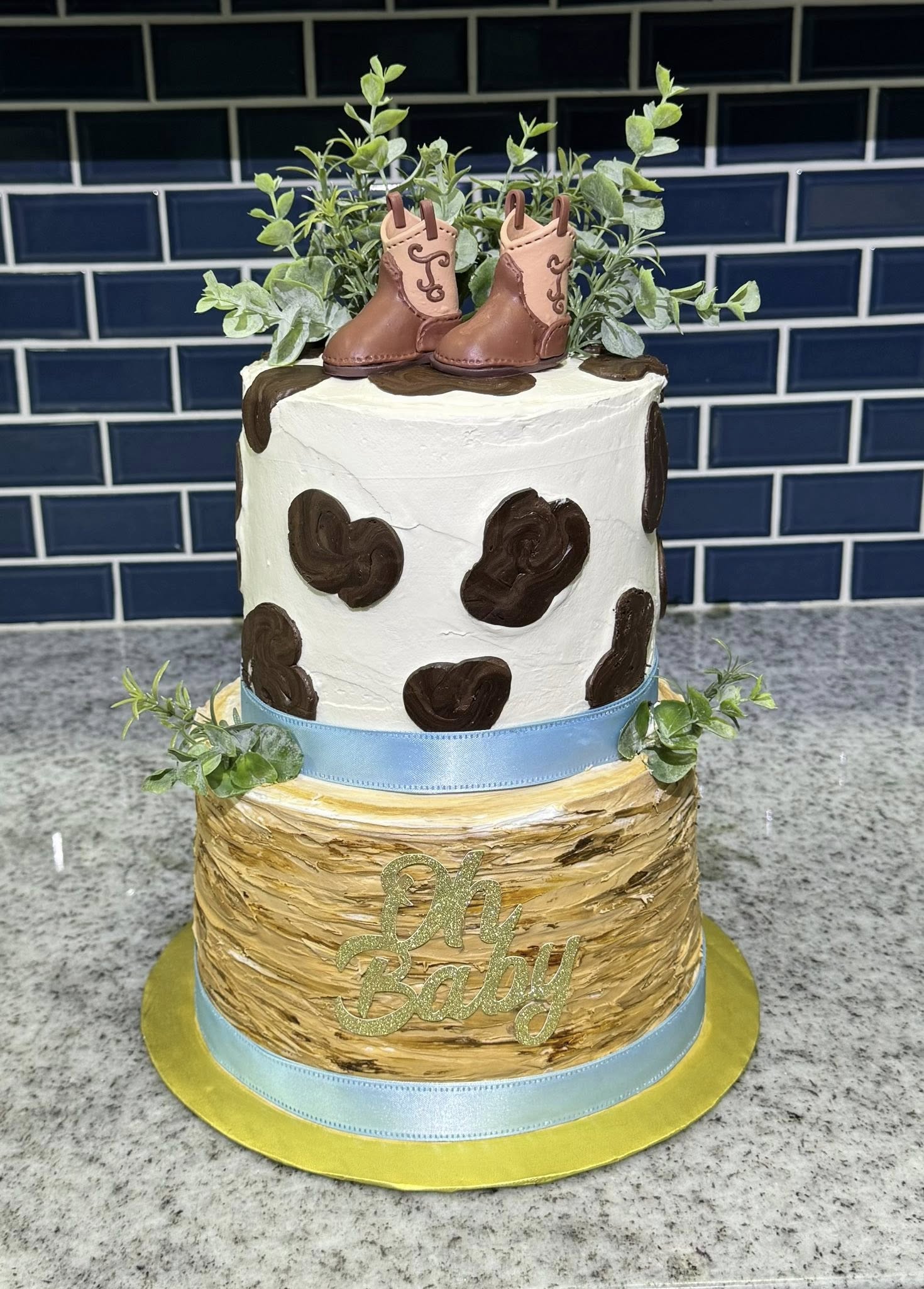 Western cowboy baby shower cake with cow print and boots topper